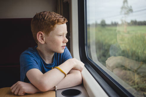 Boy looking through window while traveling in train, Thailand, Asia - NMSF00407