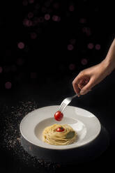 Teller mit Spaghetti und Kirschtomaten in der Gabel, gehalten von einer Frau - CAVF75884