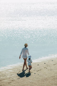 Mother and daughter walking on the beach - CAVF75990
