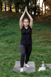 Das entspannte Mädchen macht Yoga im Park auf dem Teppich - CAVF75995