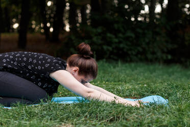 Das entspannte Mädchen macht Yoga im Park auf dem Teppich - CAVF76003