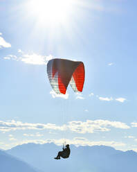 Gleitschirmfliegen bei blauem Himmel mit Sonneneinstrahlung - CAVF76044