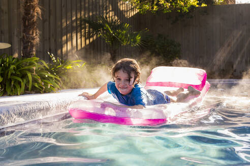 Ein kleiner Junge spielt im Pool bei Sonnenaufgang - MINF14047