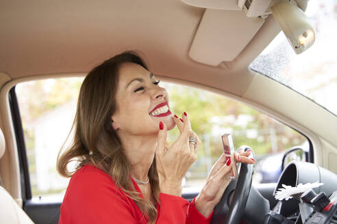 Reife Frau mit roten Lippen und Nägeln im Auto - PNEF02463