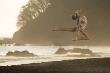 Teenage girl practicing gymnastic at seafront, Jaco Beach, Costa Rica - AMUF00008