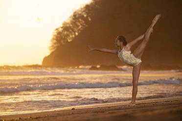 Teenage girl practicing gymnastic at seafront by sunset, Jaco Beach, Costa Rica - AMUF00011