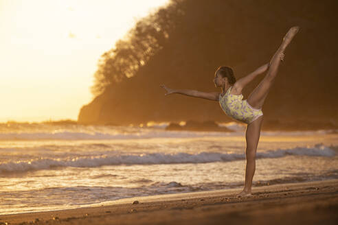 Teenager-Mädchen übt Gymnastik am Meer bei Sonnenuntergang, Jaco Beach, Costa Rica - AMUF00011