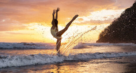 Teenage girl practicing gymnastic at seafront by sunset, Jaco Beach, Costa Rica - AMUF00012