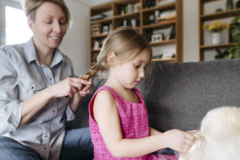 Mutter flechtet die Haare ihrer Tochter auf der Couch - VYF00002