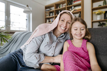 Porträt einer glücklichen Mutter und ihrer kleinen Tochter, die zusammen auf der Couch sitzen und Spaß haben - VYF00003