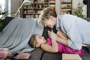 Mutter und ihre kleine Tochter spielen zusammen auf der Couch - VYF00004