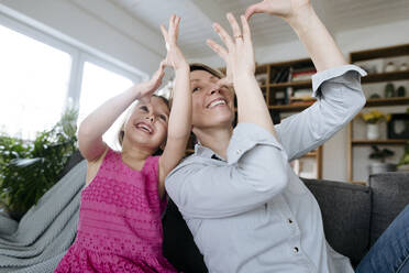 Porträt einer glücklichen Mutter und ihrer kleinen Tochter, die zusammen auf der Couch sitzen und Spaß haben - VYF00005