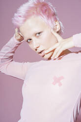 Porträt einer jungen Frau mit kurzen rosa Haaren und rosa Oberteil vor einem rosa Hintergrund - VPIF02107
