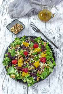 Plate of colorful mixed salad with feta cheese, common beet, walnuts, pine nuts, raspberries, oranges and corn salad - SARF04472
