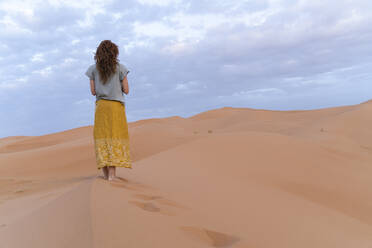 Young woman standing on sand dune in Sahara Desert, Merzouga, Morocco - AFVF05532