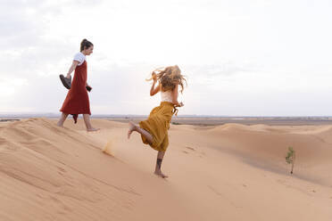 Zwei junge Frauen auf einer Sanddüne in der Wüste Sahara, Merzouga, Marokko - AFVF05543