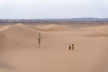 Two people climbing on sand dunes in desert stock photo