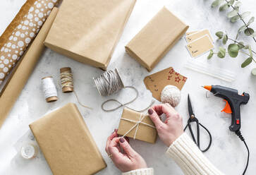 Hände einer Frau beim Einpacken von Weihnachtsgeschenken - JUNF01747