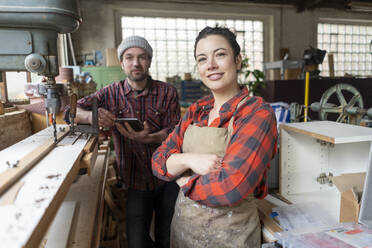 Porträt einer selbstbewussten Handwerkerin und eines Handwerkers in ihrer Werkstatt - MOEF02820