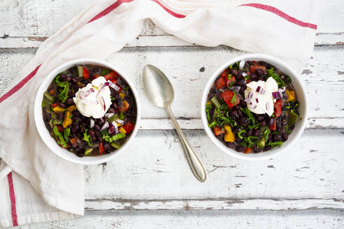 Zwei Schalen schwarze Bohnensuppe mit Paprika, Koriander, saurer Sahne und roten Zwiebeln - LVF08644