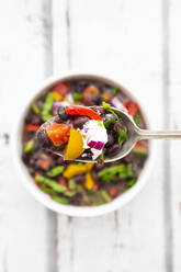 Spoon of black bean soup with bell pepper, cilantro, sour cream and red onions - LVF08647