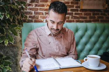 Man in a cafe taking notes - KIJF02927