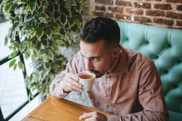 Man in a cafe drinking cup of tea - KIJF02932