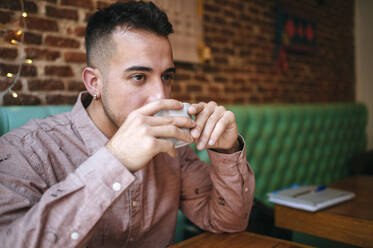 Man in a cafe drinking from cup - KIJF02933