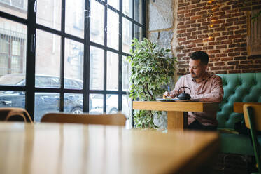 Man in a cafe taking notes - KIJF02935