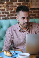 Man in a cafe using laptop - KIJF02941