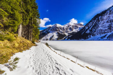 Österreich, Tirol, Tannheim, Verschneiter Wanderweg entlang des Ufers des zugefrorenen Vilsalpsees - THAF02780