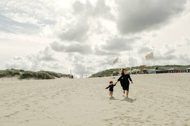 Mutter und kleine Tochter laufen Hand in Hand am Strand, Den Haag, Niederlande - OGF00162