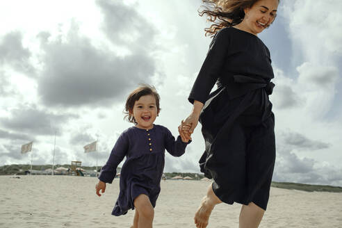 Portrait of happy little girl walking hand in hand with her mother on the beach, The Hague, Netherlands - OGF00163