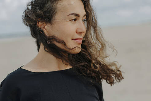 Portrait of smiling woman with blowing hair on the beach - OGF00165