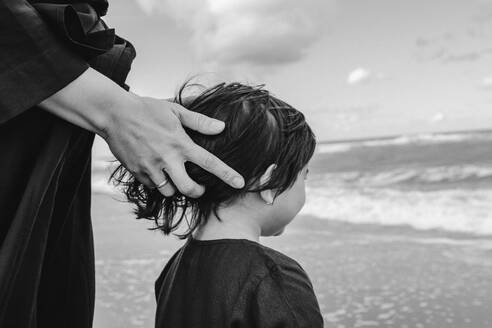 Mother's hand touching little daughter's hair on the beach - OGF00170