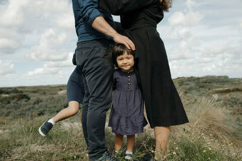 Porträt eines kleinen Mädchens, das zwischen Vater und Mutter in den Dünen steht, Den Haag, Niederlande, lizenzfreies Stockfoto