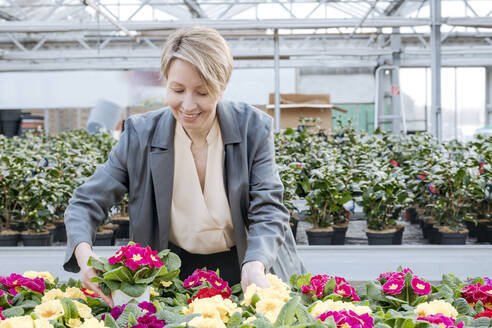 Germany, Wickede, smiling woman choosing flowers in flower shop - VYF00034