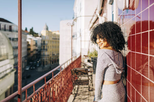 Porträt einer jungen Frau mit lockigem Haar auf einem Balkon - DCRF00095