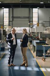 Businessman and businesswoman talking in a factory - KNSF07682