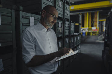 Businessman using tablet in a factory in the dark - KNSF07715