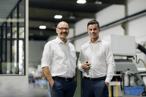 Porträt von zwei selbstbewussten Geschäftsleuten in einer Fabrik, lizenzfreies Stockfoto