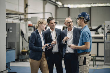 Geschäftsleute und Arbeiter im Gespräch in einer Fabrik - KNSF07744