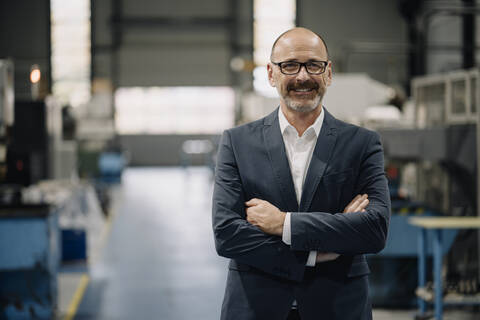 Porträt eines selbstbewussten Geschäftsmannes in einer Fabrik, lizenzfreies Stockfoto