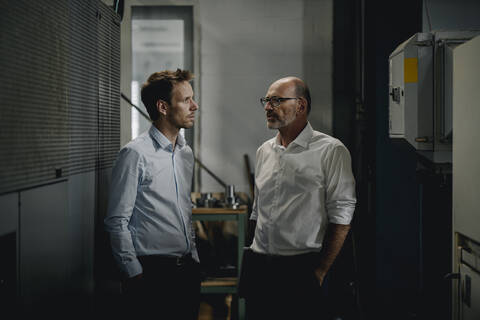 Zwei Männer unterhalten sich in einer Fabrik, lizenzfreies Stockfoto