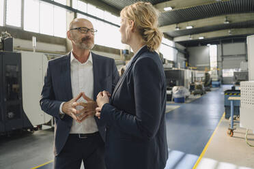 Businessman and businesswoman talking in a factory - KNSF07763