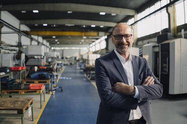 Portrait of a smiling businessman in a factory - KNSF07791