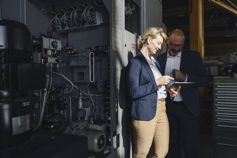 Businessman and businesswoman using tablet in a factory stock photo