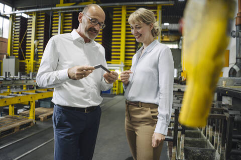 Man and woman examining workpiece in factory stock photo