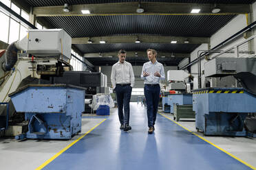 Two men walking and talking in a factory - KNSF07848