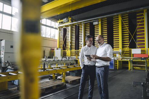 Two businessmen with tablet talking in a factory - KNSF07849